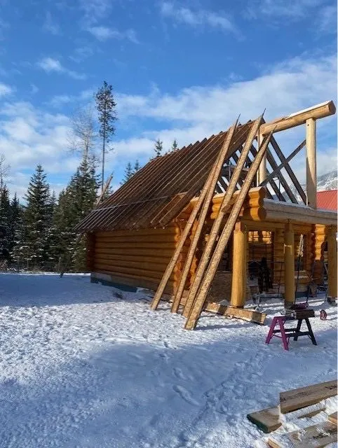 Structural ridge and rafter work on the steep-pitch log cabin roof