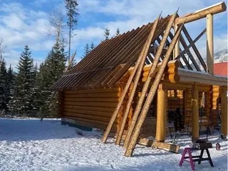 Structural ridge and rafter work on the steep-pitch log cabin roof